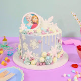 Frozen Cake with Elsa and Anna edible portraits, pastel buttercream swirls, white chocolate drip, and snowflake decorations.